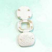 Morong exploded view showing the structural components of the compact box, including alignment pegs and the floral-embossed base.